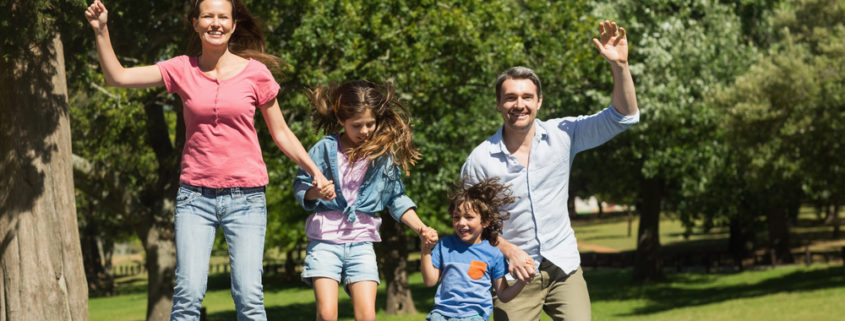 Full length of a happy family jumping high on trampoline in the park